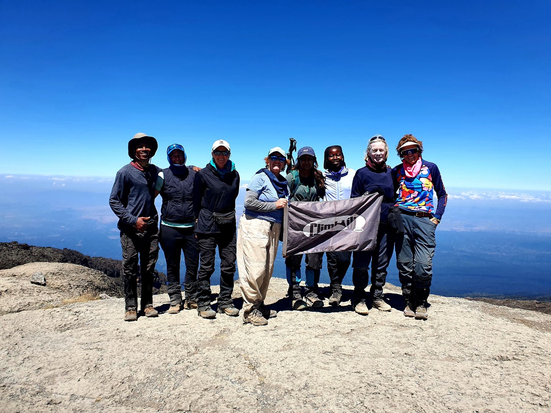The group with the Climb Kili flag high above the clouds
