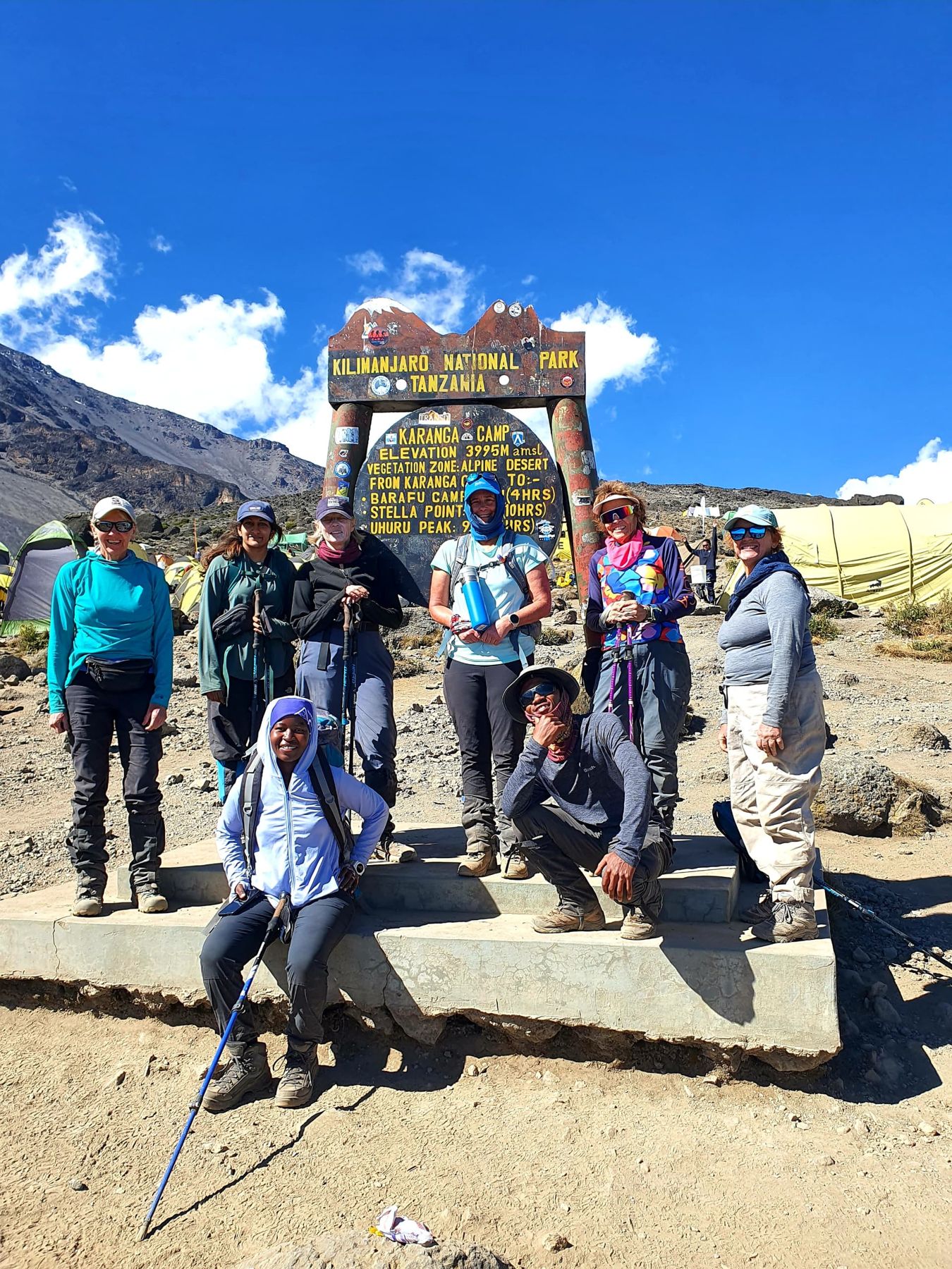 A group of smiling women at the Karanga Camp sign