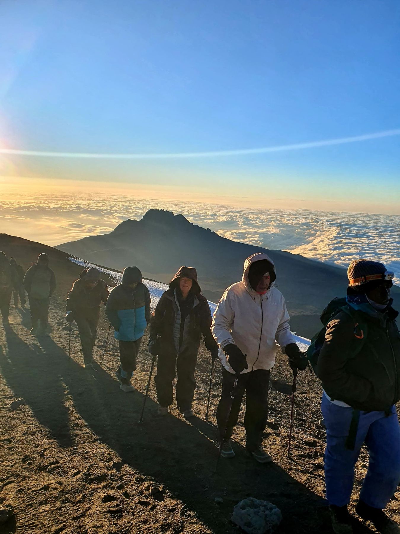 Climbers heading for the summit at sunrise above a sea of clouds